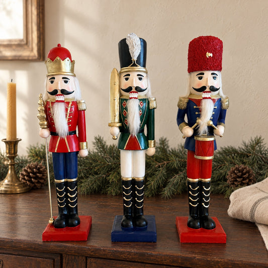 I tre schiaccianoci classici con la giacca verde, blu e rossa e gli alamari dorati, in fila su una credenza di legno fra rami di abete e pigne